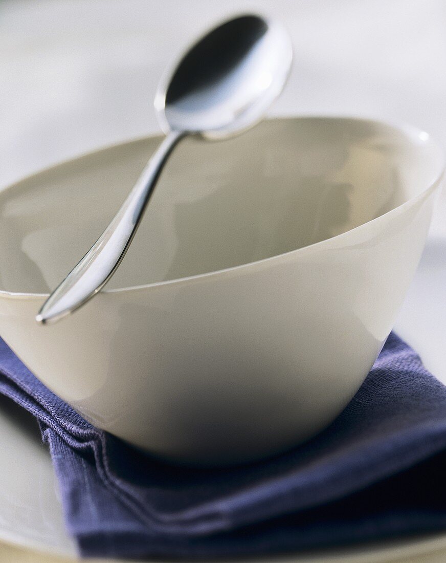White bowl with spoon on purple napkin
