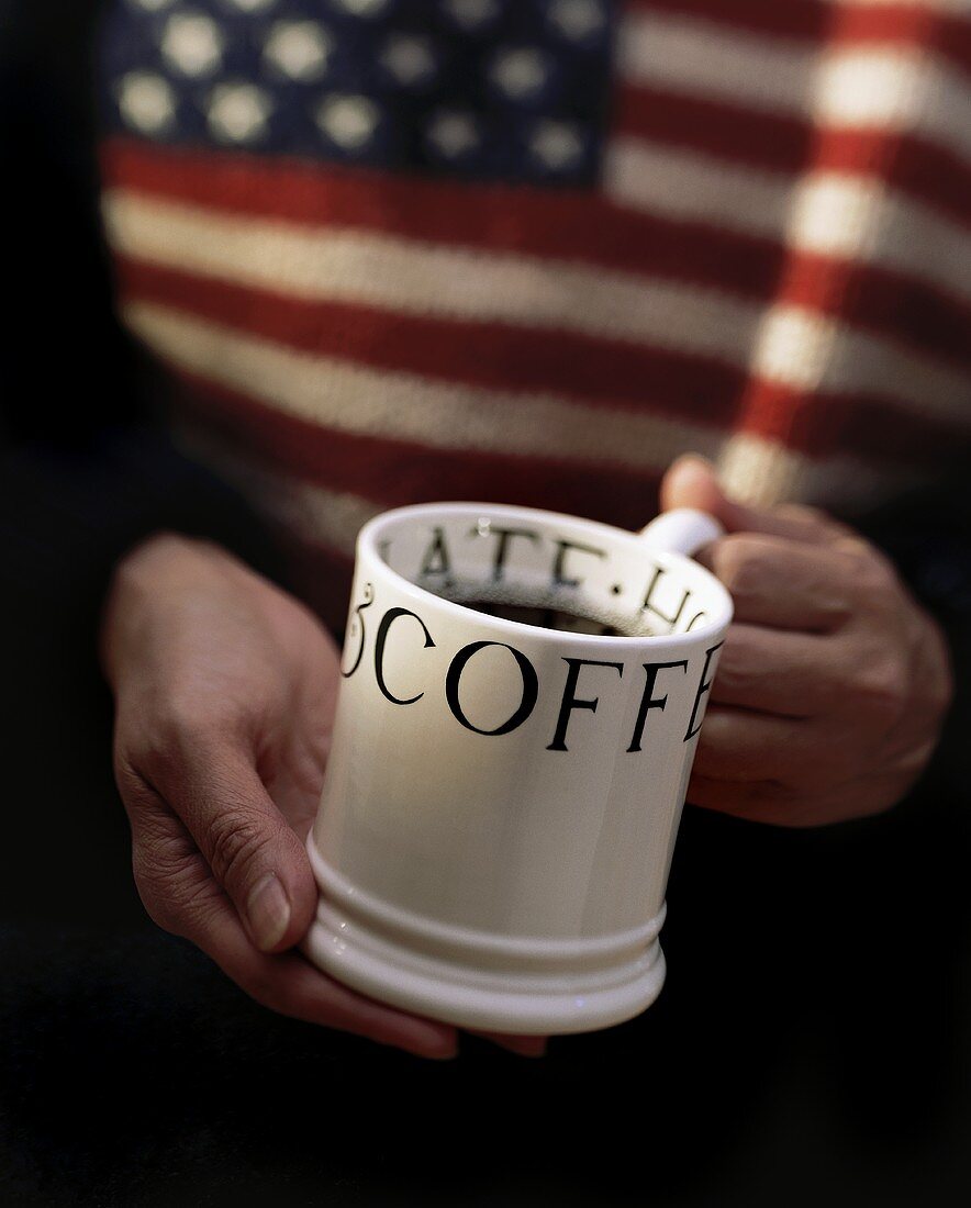 Hände halten amerikanische Kaffeetasse