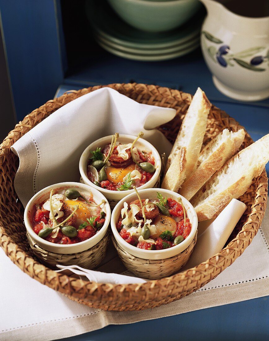 Baked egg tapas with capers and tomatoes; white bread