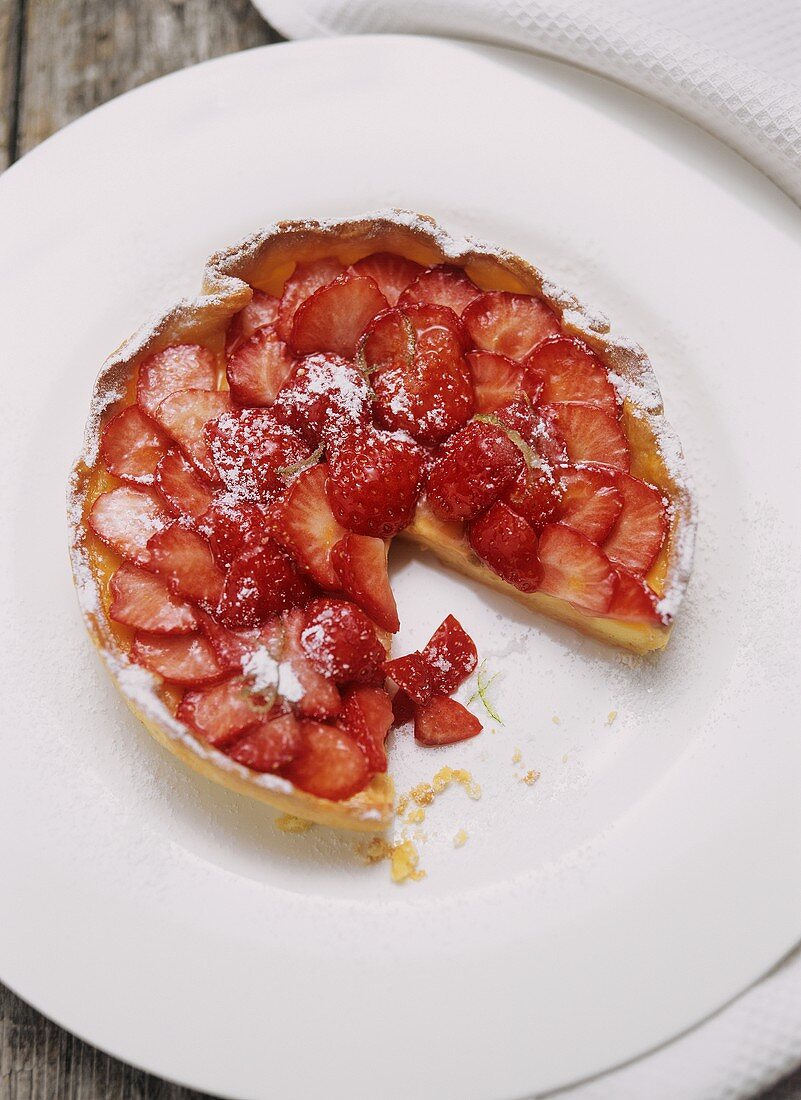 Strawberry tart with icing sugar, a piece cut