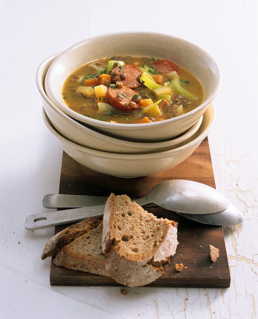 Hearty lentil soup with sausage; slices of bread