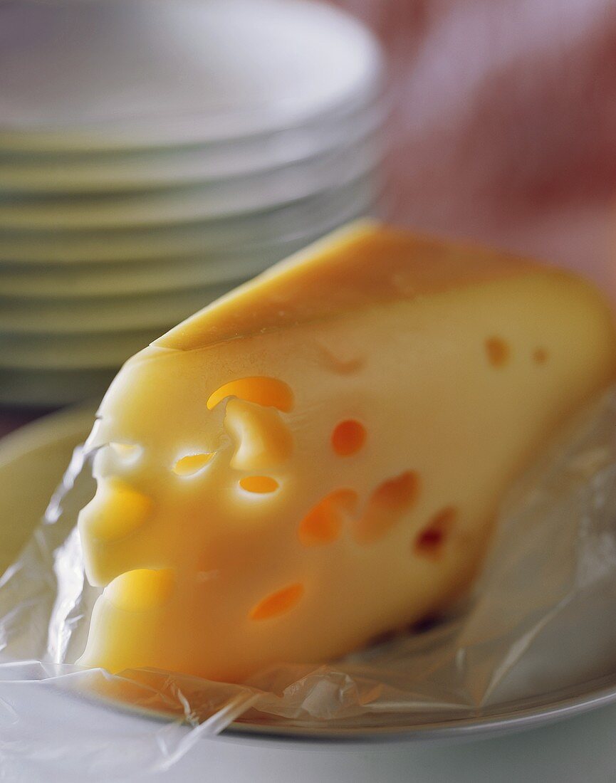 Stück Käse vor Tellerstapel