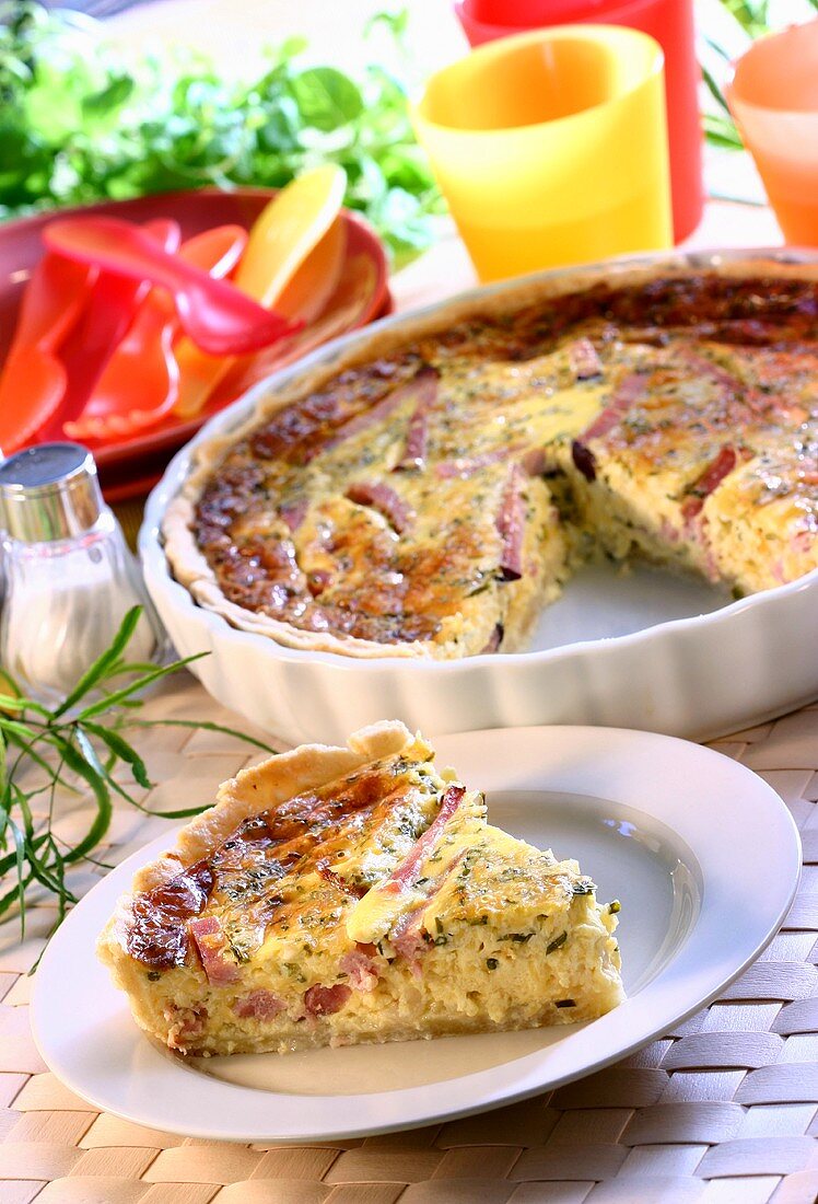 Quiche with ham in baking dish and on plate