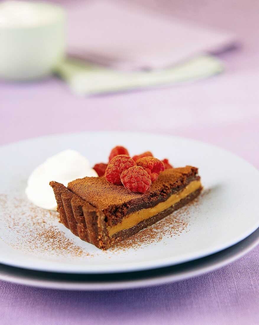 A piece of chocolate toffee tart, decorated with raspberries