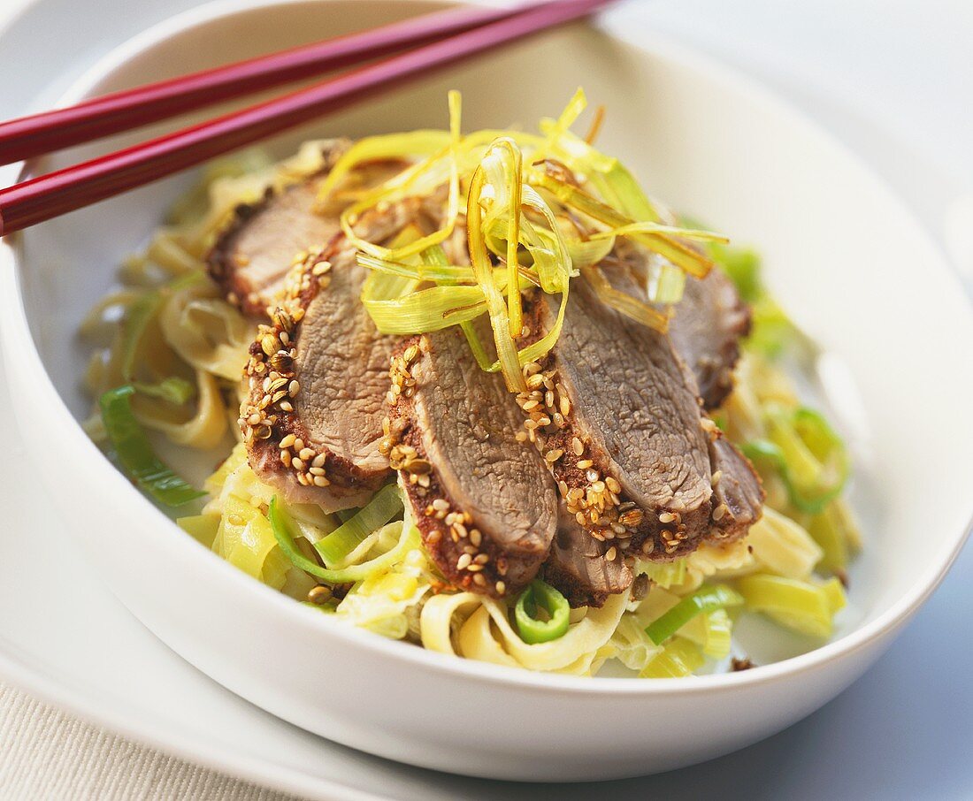 Beef with sesame crust on leeks and noodles