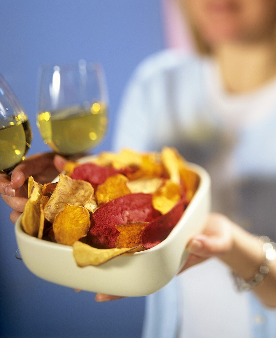 Hands holding dish with mixed crisps