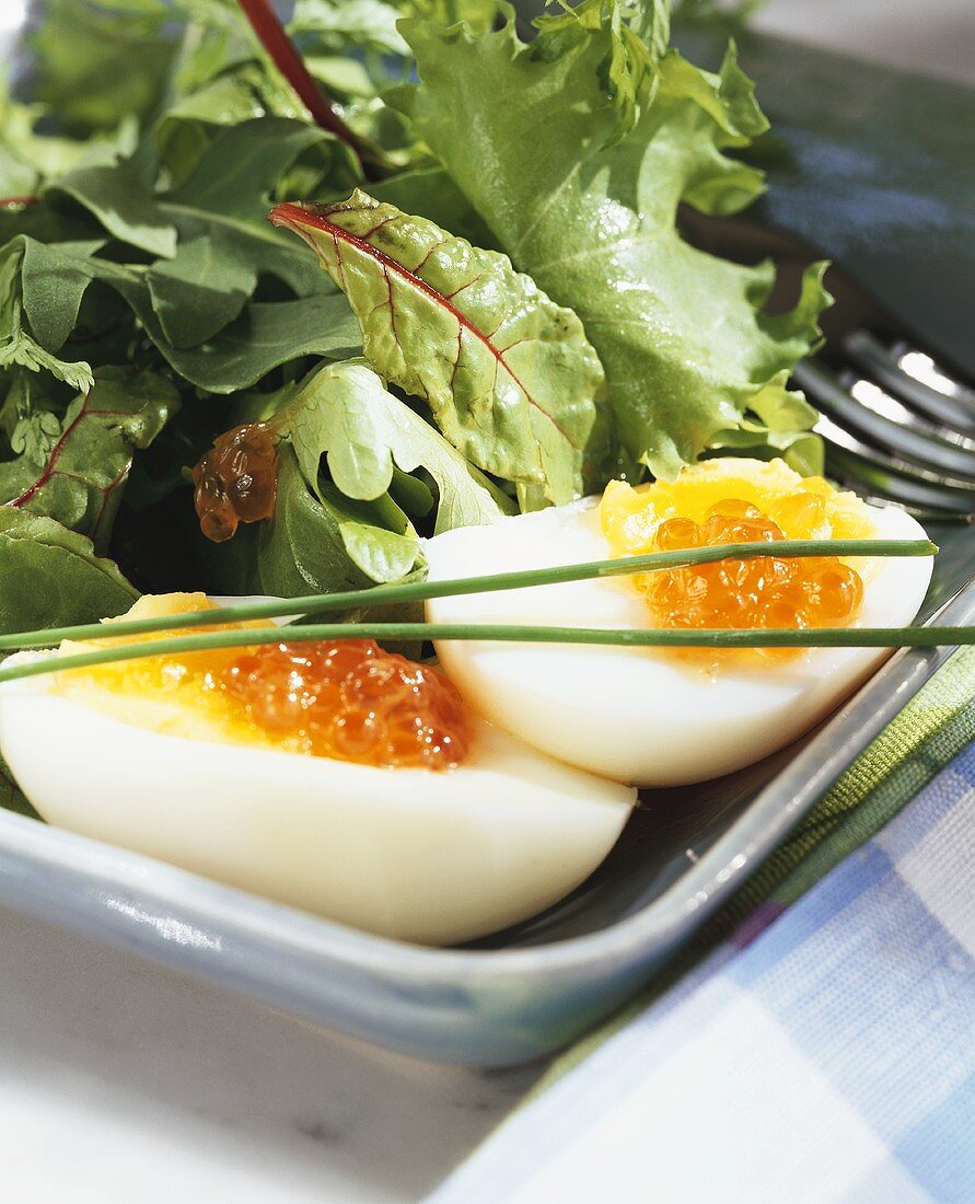Boiled eggs with salmon caviare and salad leaves