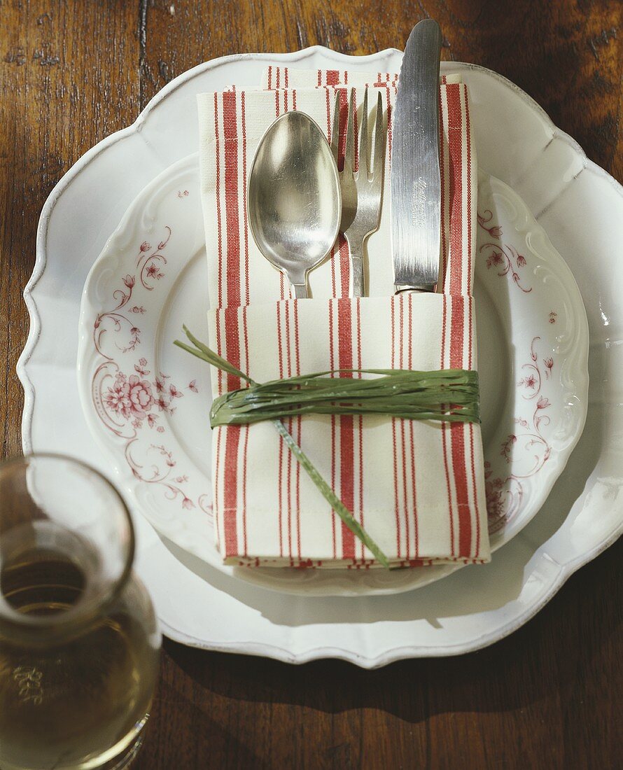 Place setting with cutlery in striped fabric napkin