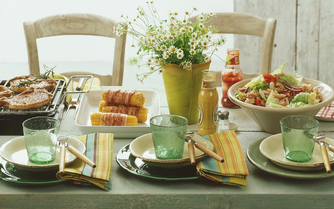 Gedeckter Tisch für eine Grillparty (Thunfischsalat, Mais)