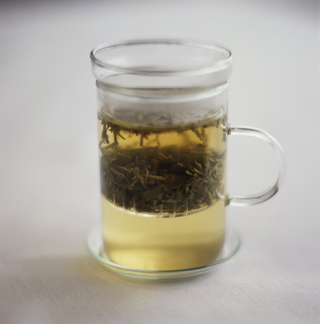 Green tea with tea leaves in glass