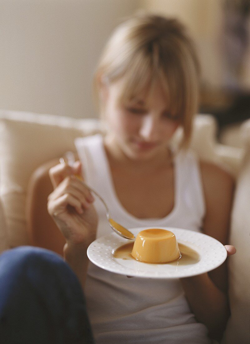 A blonde girl eating pumpkin pudding with caramel sauce