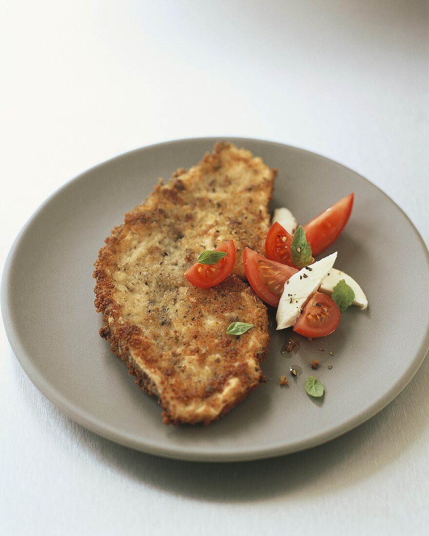 Breaded fish fillet with tomatoes, mozzarella and basil