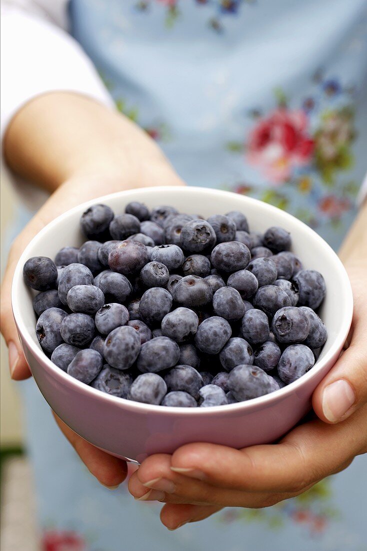 Woman holding bowl of blueberries