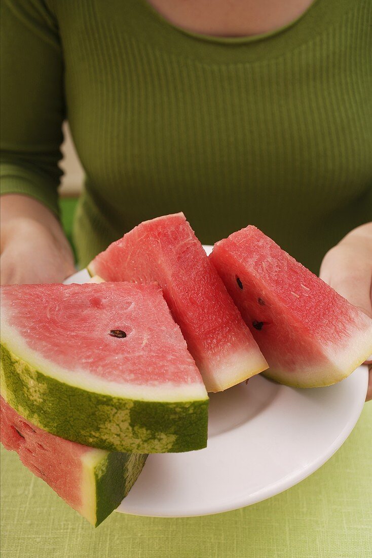 Frau hält Teller mit Wassermelonenspalten