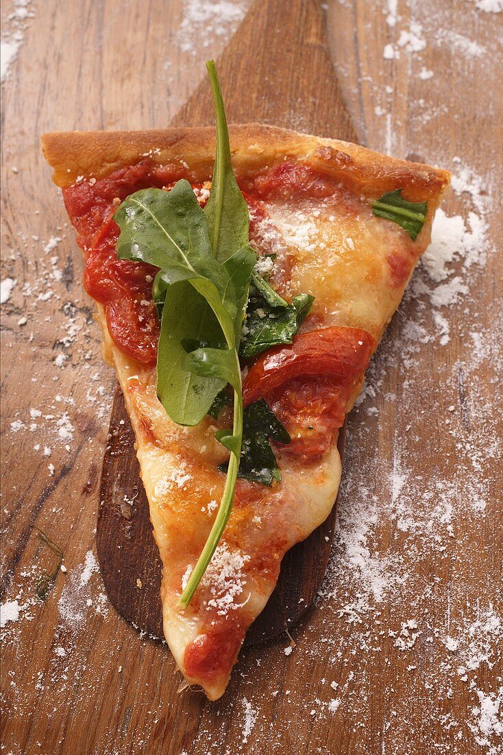 Piece of cheese and tomato pizza with rocket