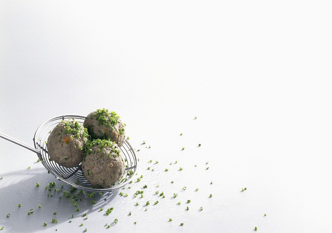 Liver dumpling with snipped chives on skimmer