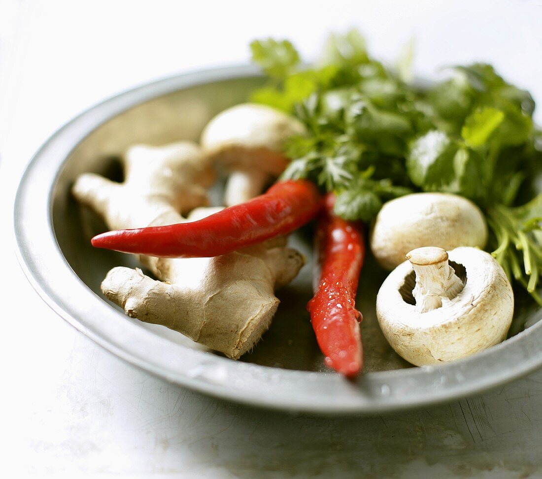 Ginger root, chillies, mushrooms, coriander leaves on plate