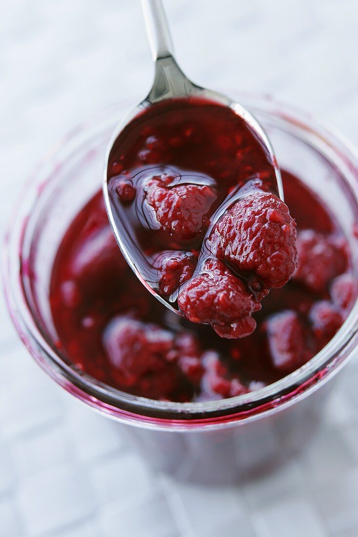 Raspberry compote on spoon and in glass