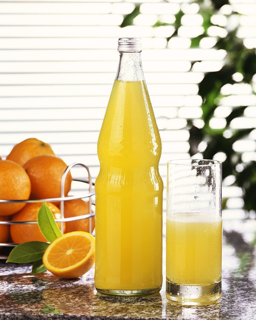 Orangenlimonade in Glas und Flasche