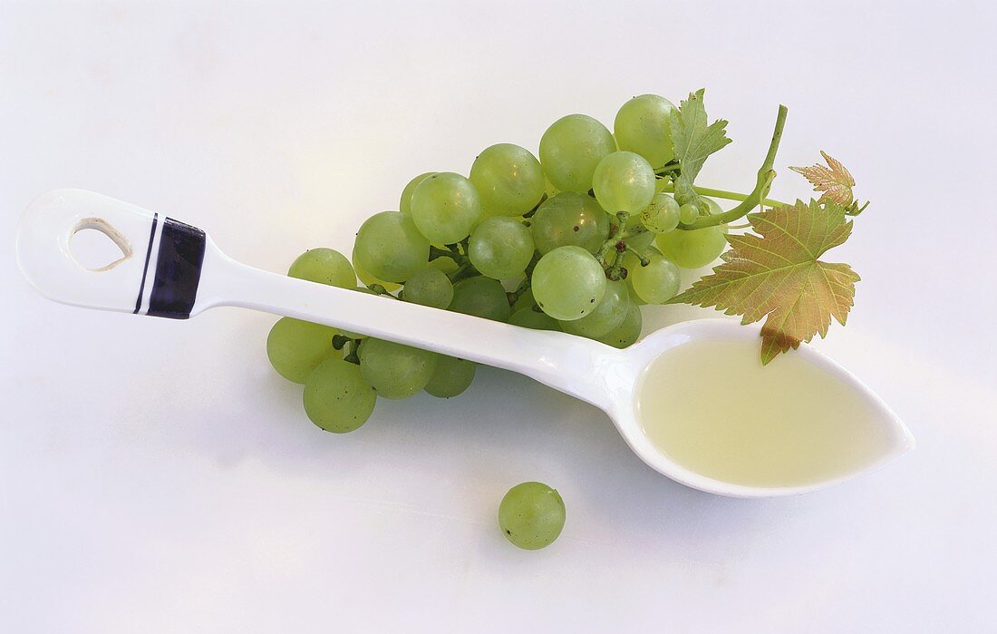 Grape seed oil on spoon beside green grapes