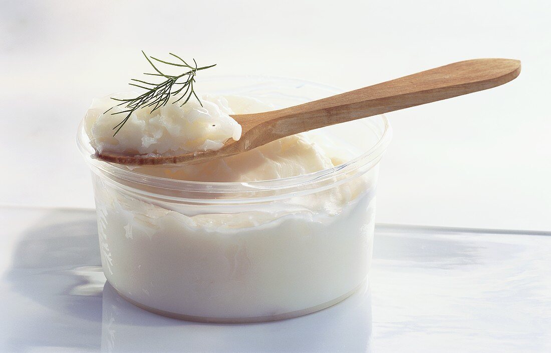 Goose fat in plastic tub and on wooden spoon