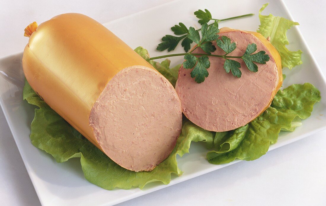 Liver sausage, a piece cut, on lettuce leaves