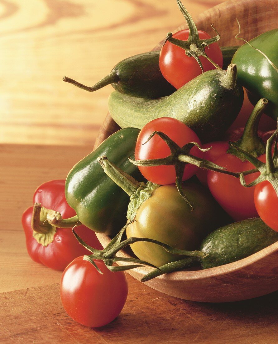 Peppers, tomatoes and cucumbers in wooden bowl