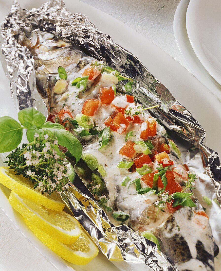 Trout in foil with tomatoes, herbs and sour cream