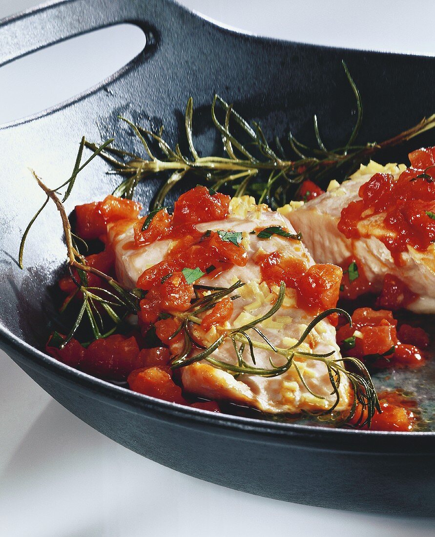 Salmon fillet with tomatoes and rosemary in wok