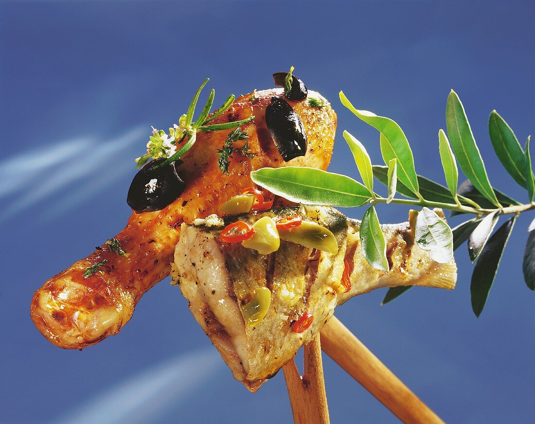 Fish and chicken leg with olives on wooden forks