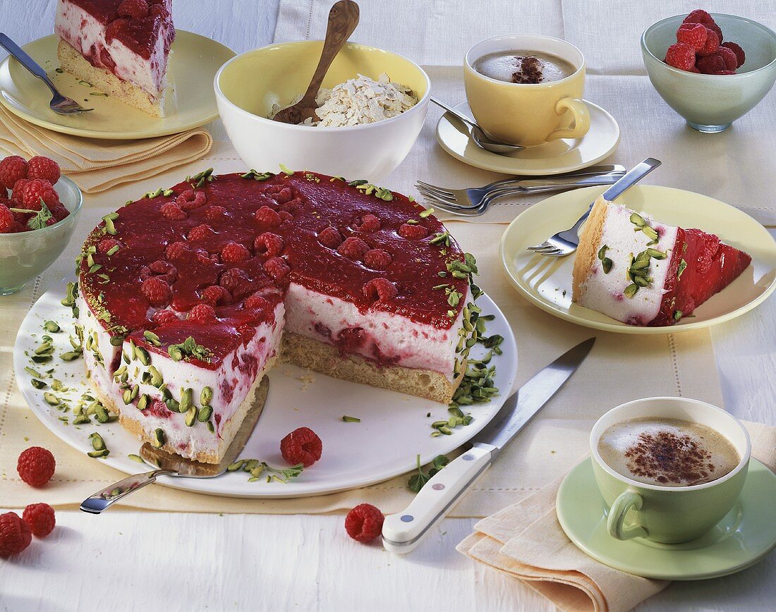 Raspberry cake with pistachios, pieces taken, and cappuccino