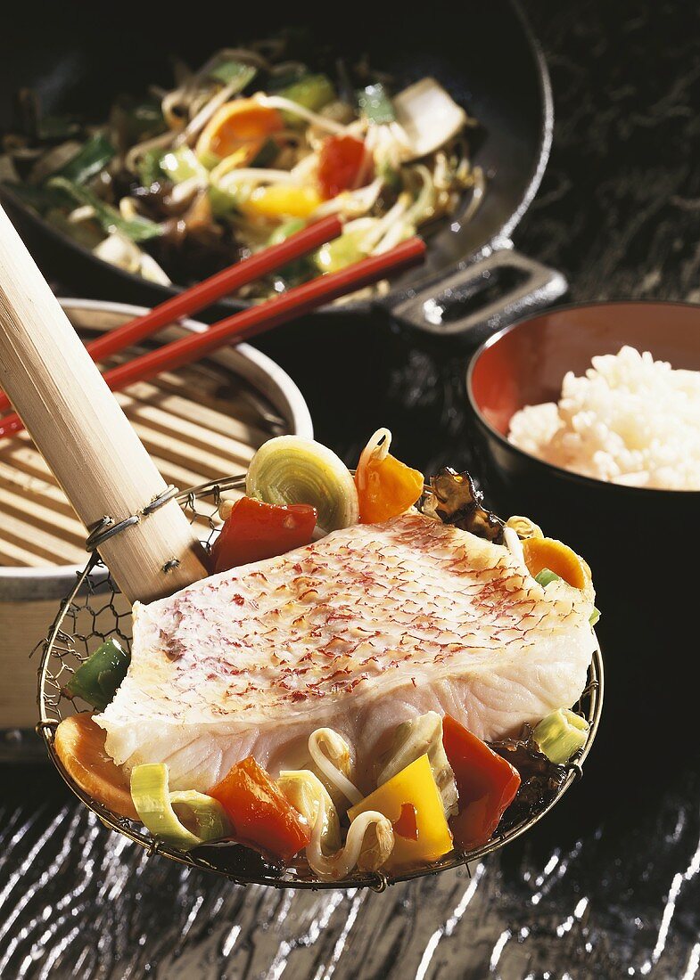 Redfish with wok vegetables on ladle