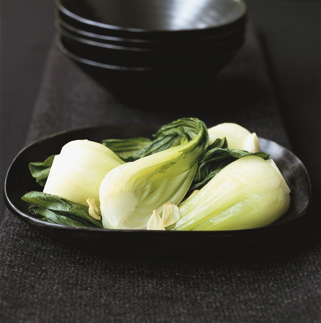 Cooked pak choi with garlic on black plate