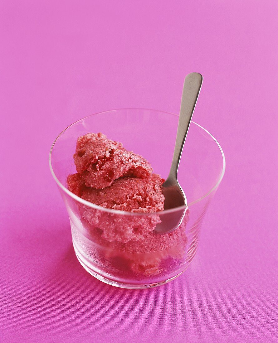 Raspberry ice cream in glass with spoon