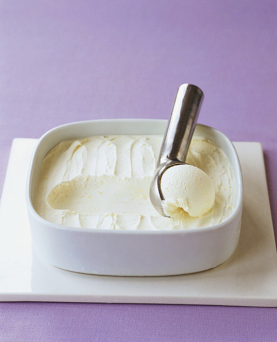 Lemon ice cream in bowl with ice cream scoop