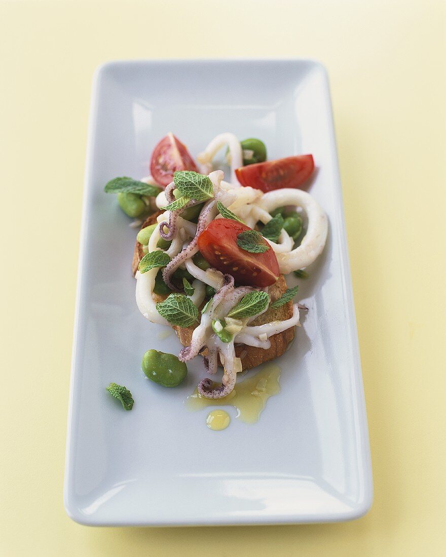 Tintenfisch-Tomaten-Salat mit frischer Minze auf Brotscheibe
