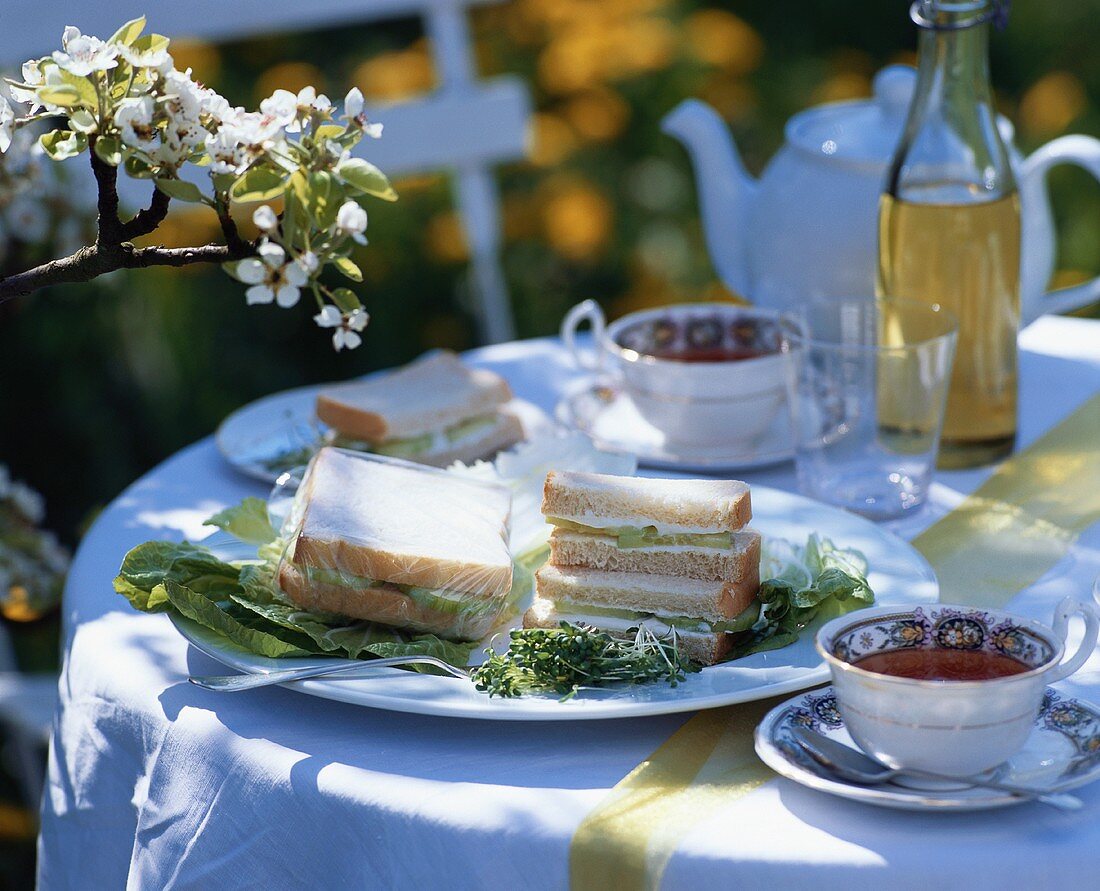 Gurkensandwiches und Tee auf Tisch im Freien