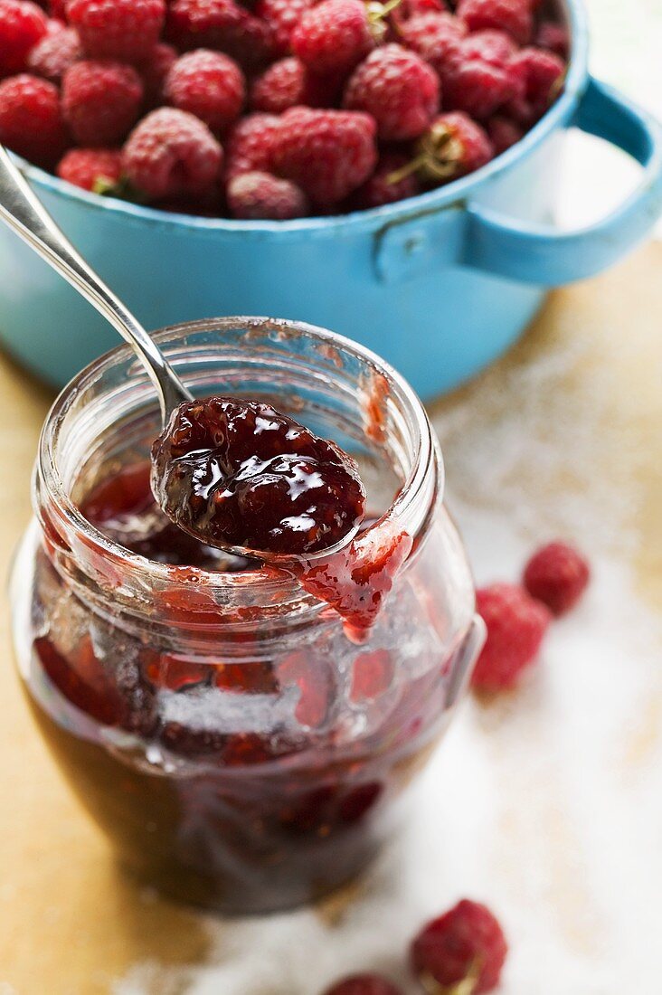 Glas Himbeermarmelade, Zucker und frische Himbeeren