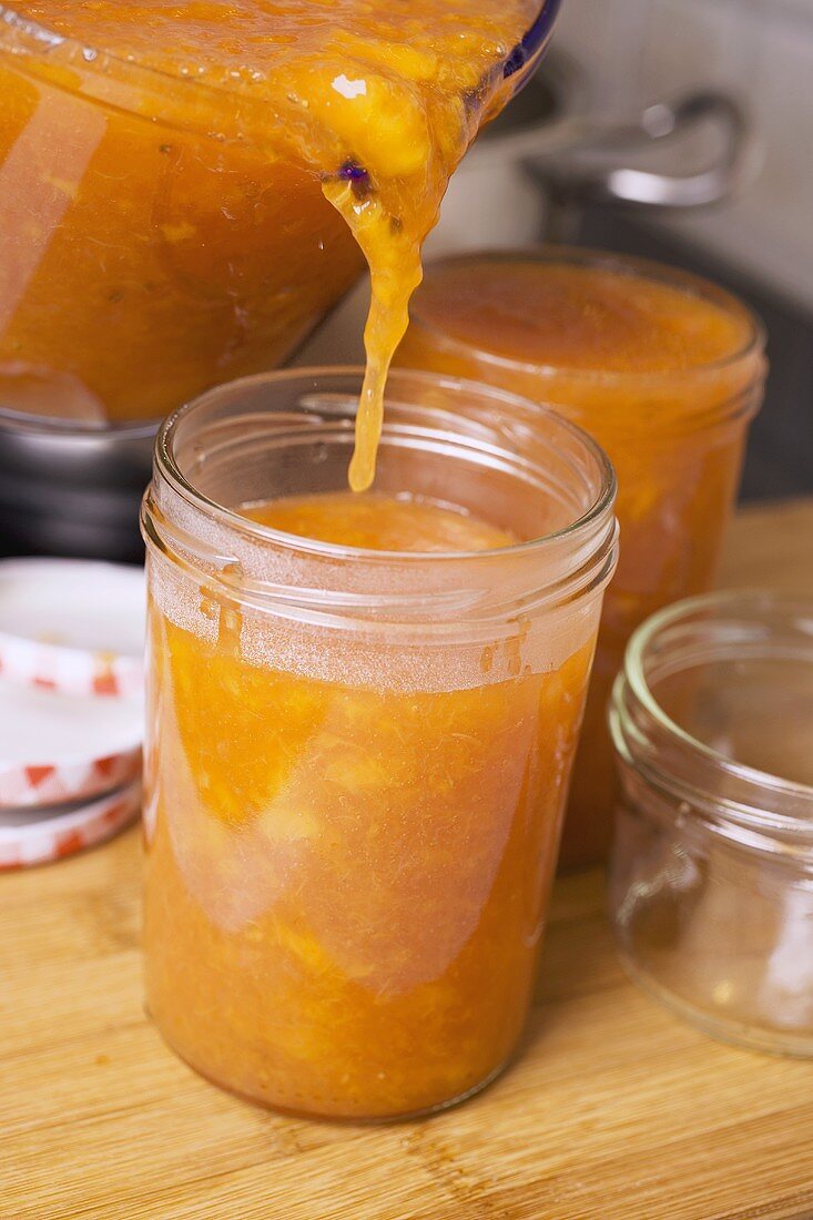 Pouring nectarine jam into jars