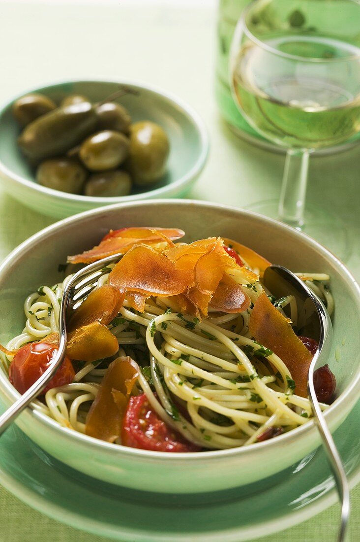 Spaghetti with bresaola and tomatoes, green olives in bowl