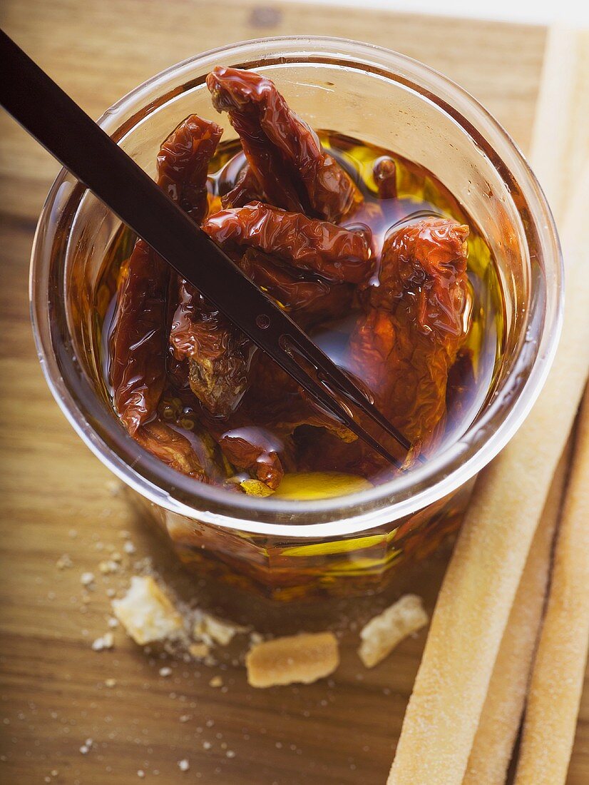 Dried tomatoes in oil, grissini beside them