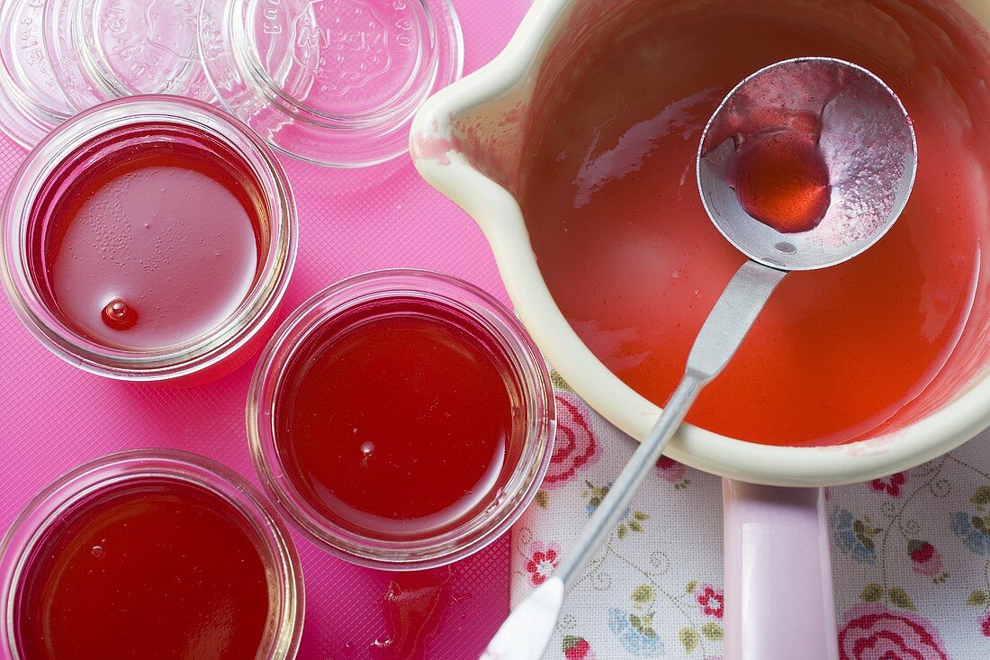 Redcurrant jelly in a pan and three jars