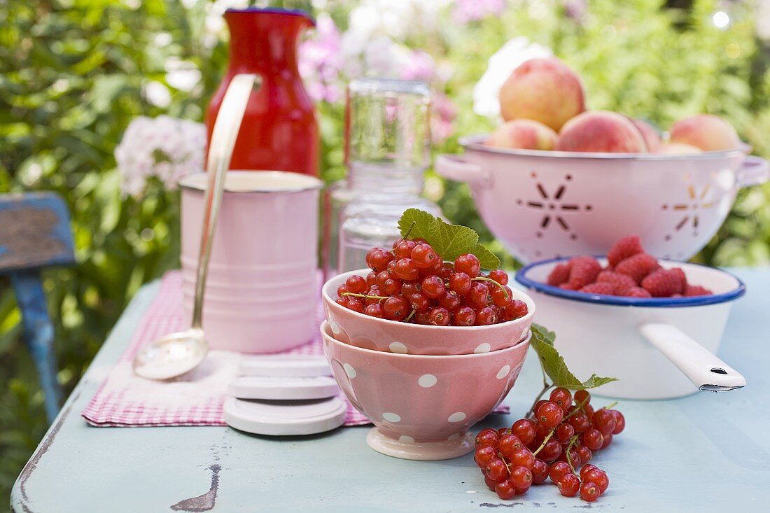 Pfirsiche, Beeren und Einmachgläser auf Gartentisch