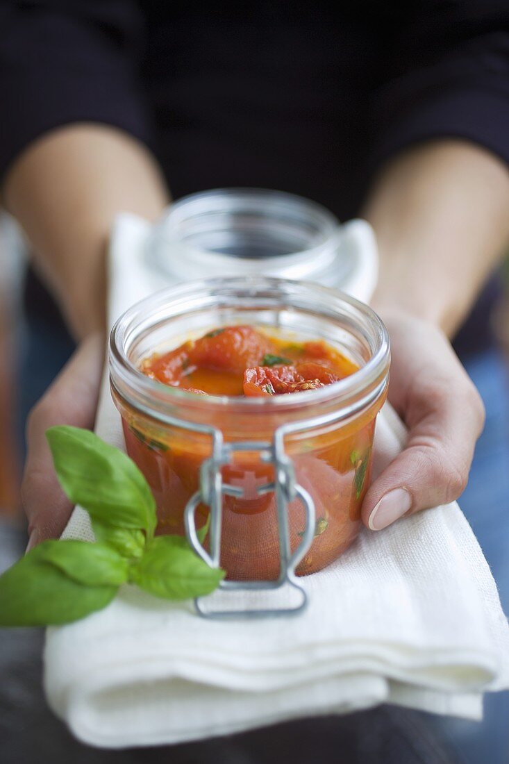 Hände halten Glas mit selbstgemachter Tomatensauce