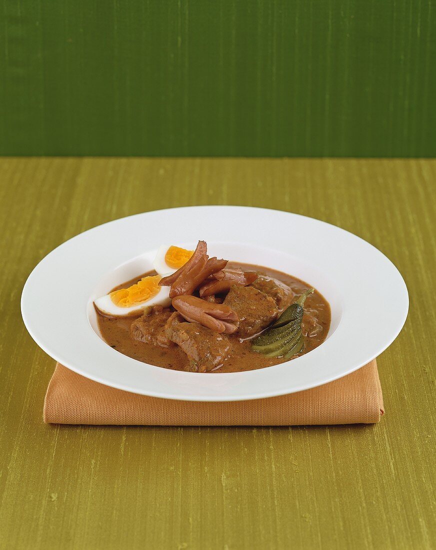 Beef goulash with frankfurters, egg and gherkins