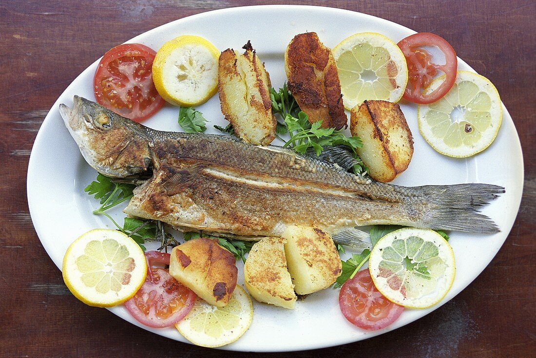 Fried fish with potatoes, tomatoes and lemon
