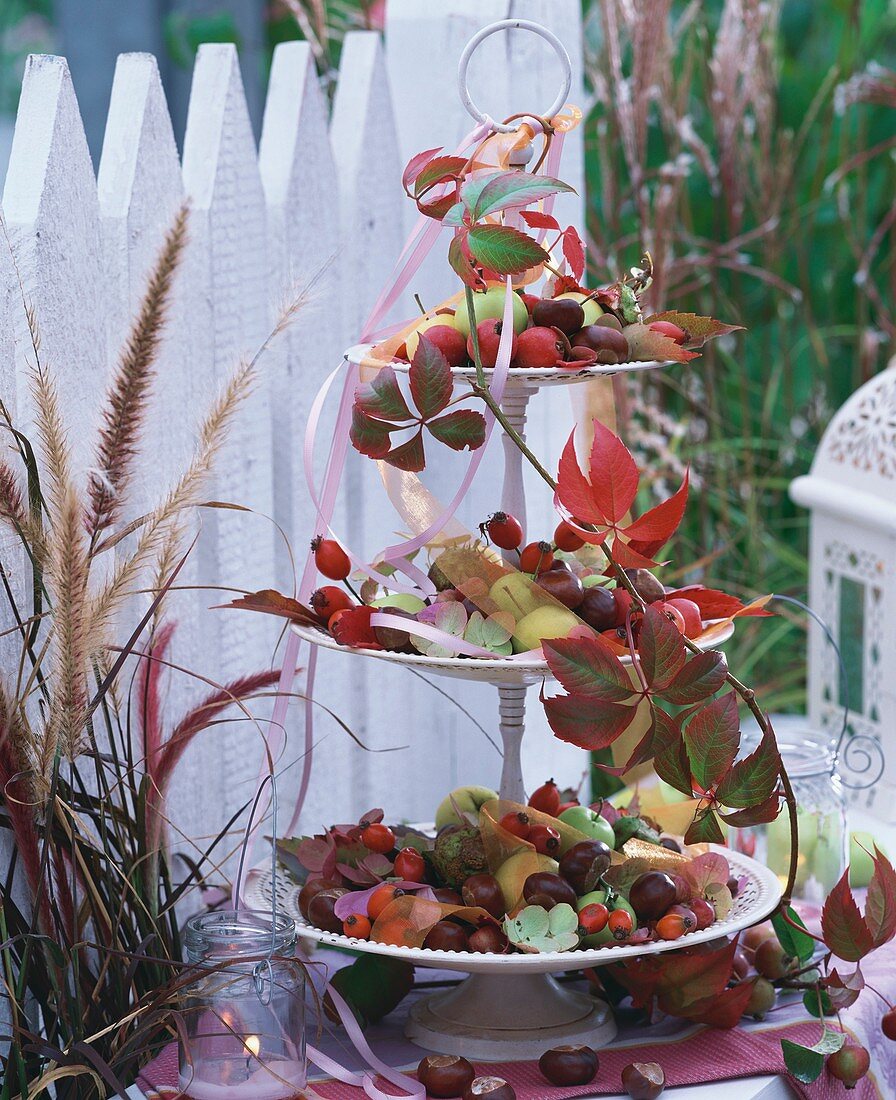 Etagere mit Hagebutten, Kastanien, Hortensien und Herbstlaub