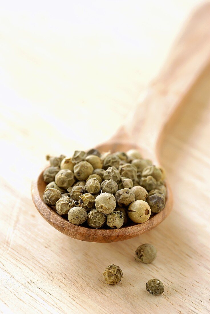 Green peppercorns on wooden spoon