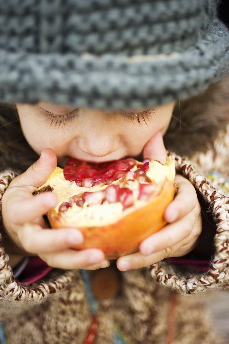 Child biting into pomegranate