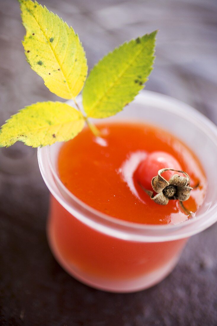 Hagebuttenmarmelade im Glas mit frischer Hagebutte und Blatt